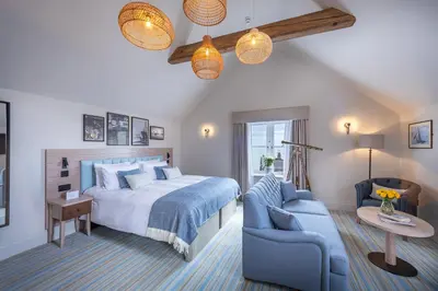 a bedroom with a large bed and a blue couch at The Ship Hotel in Southend-on-Sea