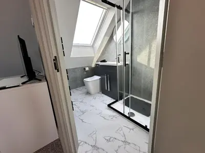 a bathroom with a glass shower and a toilet at Abbey Rooms in Waltham Abbey