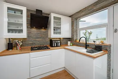 a kitchen with white cabinets and a window at Coastal Charm In Clacton On Sea in Holland-on-Sea