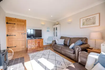 a living room with a couch and a television at The Meadows Dairy, Bawdsey in Bawdsey