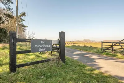 a sign on a fence next to a road at The Meadows Dairy, Bawdsey in Bawdsey