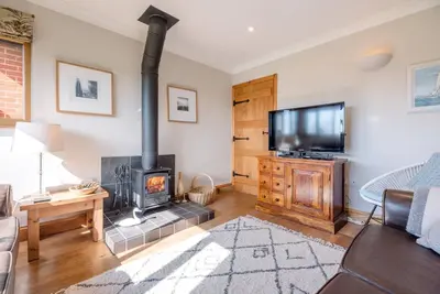 a living room with a fireplace and a flat screen tv at The Meadows Dairy, Bawdsey in Bawdsey