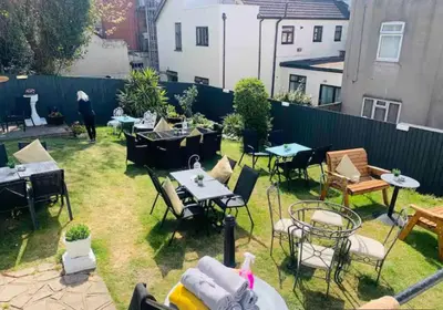 a backyard with tables and chairs and a fence at The Cobham Hotel in Southend-on-Sea
