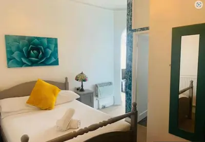 a bedroom with a bed with a yellow pillow and a mirror at The Cobham Hotel in Southend-on-Sea