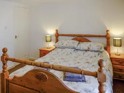 a bedroom with a wooden bed with two night stands at Cosy Cottage in Manningtree