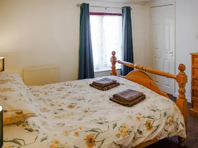 a bedroom with a bed with a floral bedspread at Cosy Cottage in Manningtree