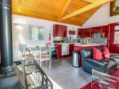 a living room with a couch and a kitchen at Rookyard Cottage in Halesworth