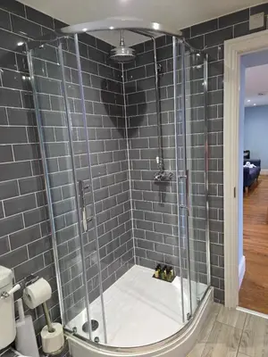 a shower in a bathroom with gray tiles at Little George in Rayne