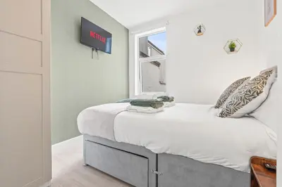a bedroom with a bed with a tv on the wall at Cozy accessible 2bd flat on Mill road with firepit for a lovely winters night in Cambridge