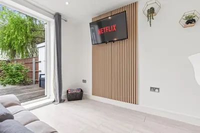 a living room with a couch and a sign on the wall at Cozy accessible 2bd flat on Mill road with firepit for a lovely winters night in Cambridge