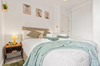 a bedroom with a bed with a blue blanket on it at Cozy accessible 2bd flat on Mill road with firepit for a lovely winters night in Cambridge