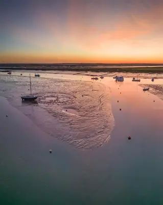 a group of boats in the water on a beach at The Beach House East Mersea in Mersea Island