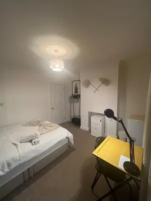 a bedroom with a bed and a desk and a lamp at Golden House in Waterbeach