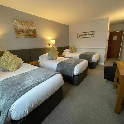 a hotel room with three beds and a couch at The White Hart Hotel Witham in Witham