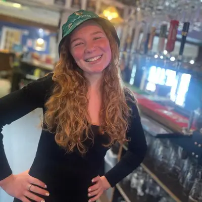a woman is smiling while wearing a green hat at The White Hart Hotel Witham in Witham