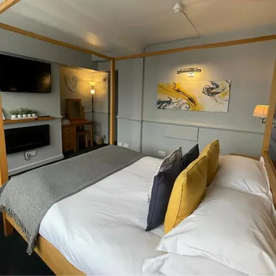 a bedroom with a large white bed and a television at The White Hart Hotel Witham in Witham