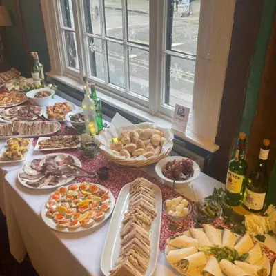 a table with many plates of food and bottles of wine at The White Hart Hotel Witham in Witham
