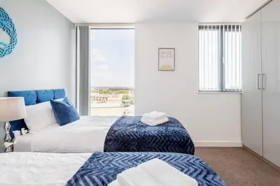 a bedroom with two beds and a large window at Penthouse Panoramic 2 Bedroom -Basildon Essex in Laindon