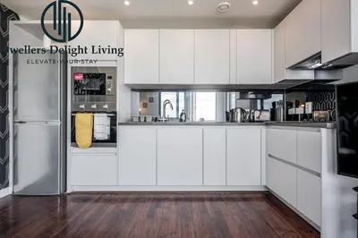 a kitchen with white cabinets and a refrigerator at Penthouse Panoramic 2 Bedroom -Basildon Essex in Laindon