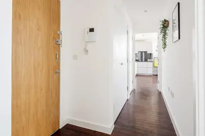 a hallway with white walls and a wooden door at Penthouse Panoramic 2 Bedroom -Basildon Essex in Laindon