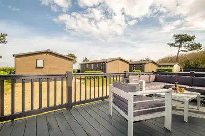 a deck with a couch and a table at Driftwood Lodge, Sizewell - Adults only property - Aldeburgh Coastal Cottages in Sizewell
