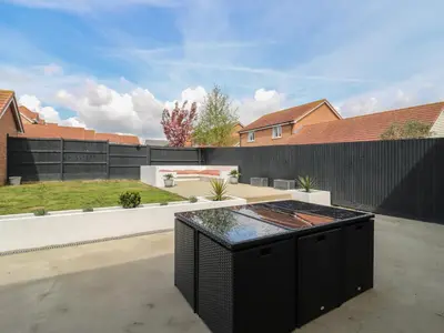 a backyard with a black fence and a barbecue grill at 21 Skippers Way in Walton-on-the-Naze