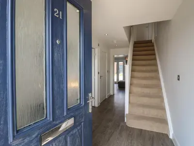 a hallway with a blue door and a staircase at 21 Skippers Way in Walton-on-the-Naze