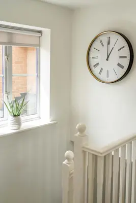 a clock hanging on a wall next to a window at Loughton Hideaway: Cozy 1BD Near Tube & Nature in Theydon Bois