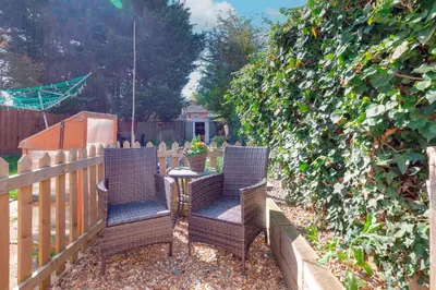 a patio with two chairs and a table next to a fence at Pass the Keys Stylish and modern apartment in Cambridge
