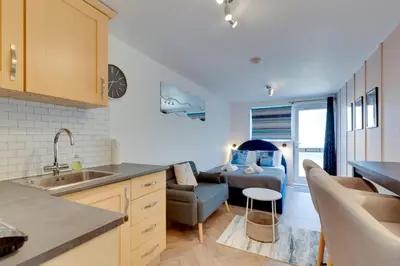 a kitchen with a sink and a living room at Pass the Keys Stylish and modern apartment in Cambridge