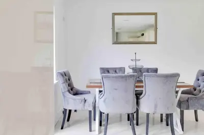 a dining room with a table with chairs and a mirror at Wayside Warren Harlow in Potter Street