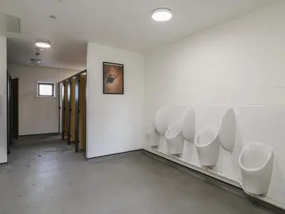 a bathroom with a row of urinals on the wall at Buttercup Cow Shed 3 in Woodbridge