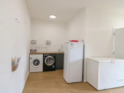 a laundry room with a refrigerator and a washing machine at Buttercup Cow Shed 3 in Woodbridge