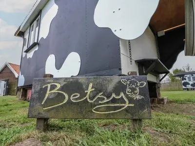 a sign with graffiti on it in front of a house at Betsy Cow Shed 2 in Woodbridge
