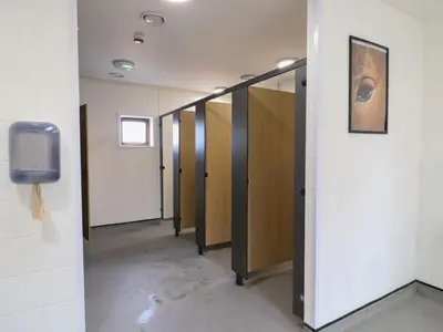 a row of stalls in a hallway with a tv at Bluebelle Cow Shed 5 in Woodbridge