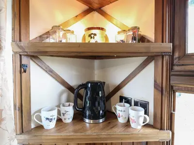a wooden shelf with cups and a coffee pot on it at Daisy Cow Shed 1 in Woodbridge