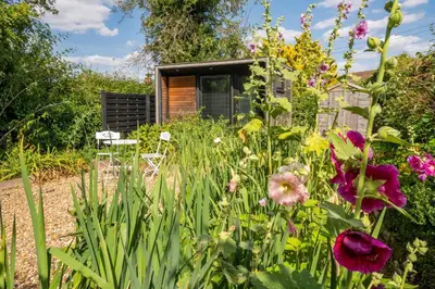 a garden with flowers in front of a house at Hylton Cottage, Lavenham in Lavenham
