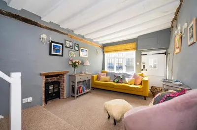 a living room with a yellow couch and a fireplace at Hylton Cottage, Lavenham in Lavenham