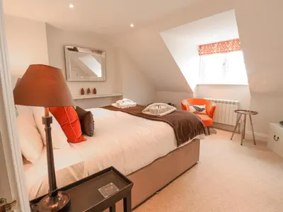 a bedroom with a large bed with an orange chair at Sea Crest in Aldeburgh