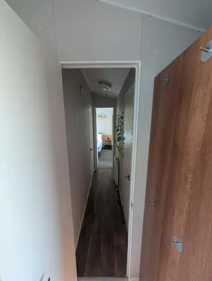 a hallway leading to a room with wood floors and a door at LuKa25 GC080 in Saint Osyth