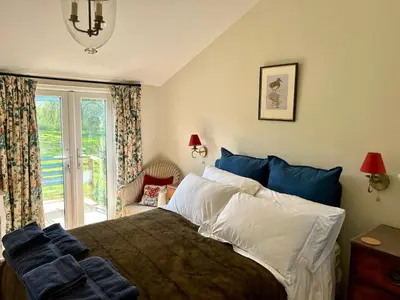 a bedroom with a large bed and a window at Giffords Hall Garden Room in Shimpling