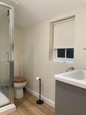 a white bathroom with a toilet and a sink at Giffords Hall Garden Room in Shimpling