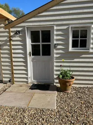 a white house with a door and a potted plant at Giffords Hall Garden Room in Shimpling