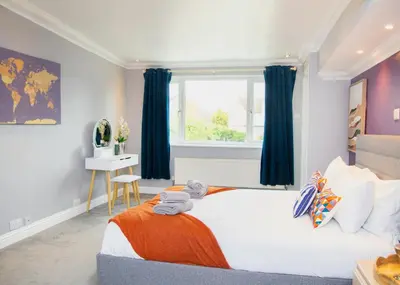 a bedroom with a large bed with blue curtains at Stylish and Spacious 3-Bed House Free Parking in Ipswich