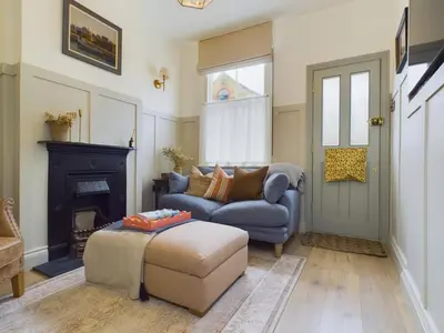 a living room with a blue couch and a fireplace at Stunning Heritage Cottage- The Heart of Old Leigh in Southend-on-Sea