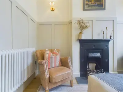 a living room with a chair and a fireplace at Stunning Heritage Cottage- The Heart of Old Leigh in Southend-on-Sea