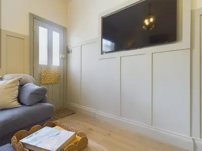 a living room with a couch and a tv on a wall at Stunning Heritage Cottage- The Heart of Old Leigh in Southend-on-Sea
