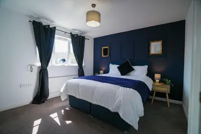 a blue bedroom with a bed and a window at Spacious 5 Bedrooms Sleeps 9 3 Bath and Parking Ideal for Contractors in Chesfield