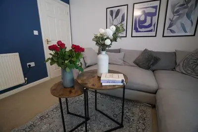 a living room with a couch and two tables with flowers at Spacious 5 Bedrooms Sleeps 9 3 Bath and Parking Ideal for Contractors in Chesfield