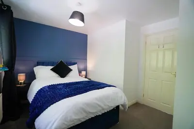 a bedroom with a bed with a blue wall at Spacious 5 Bedrooms Sleeps 9 3 Bath and Parking Ideal for Contractors in Chesfield